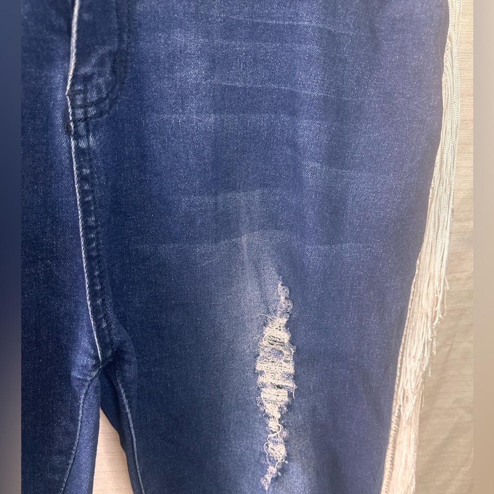 Distressed stretch denim jeans with fringe.